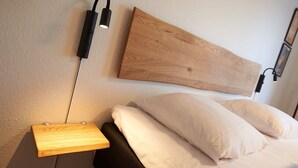 Un lit bien fait, avec du linge de lit blanc, une tête de lit en bois et une table de chevet avec une lampe.
