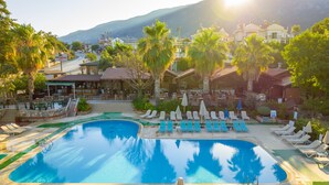 A resort with a large swimming pool, sun loungers, and palm trees. - Pink Palace Hotel (Fethiye)