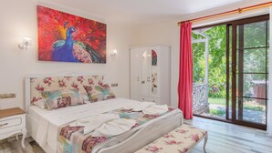 A bedroom with a bed, a bench, a wardrobe, and a peacock painting. - Pink Palace Hotel (Fethiye)