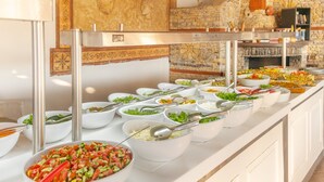 A buffet with various food items in white bowls, a stone wall, and a wooden ceiling. - Pink Palace Hotel (Fethiye)