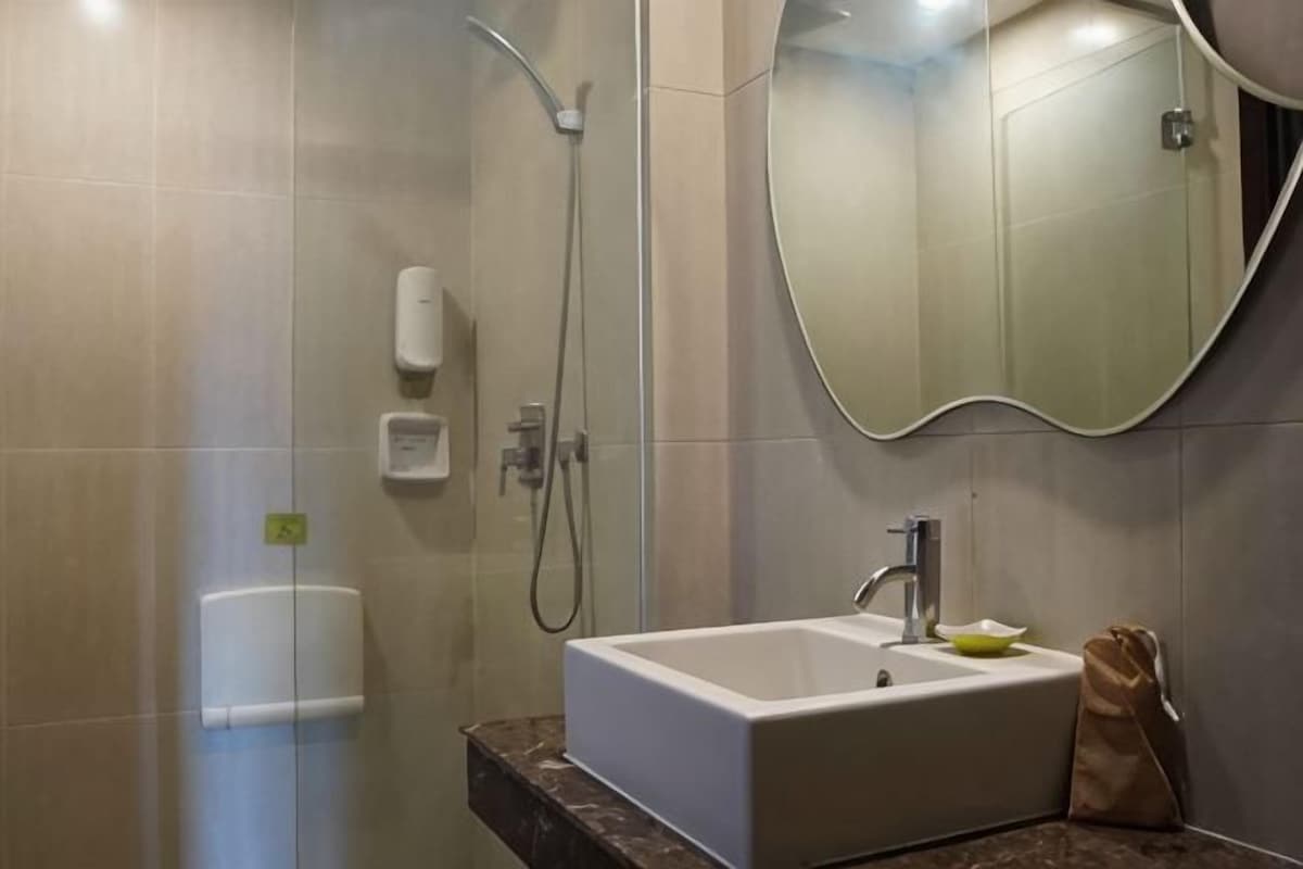A bathroom with a shower, a sink, a mirror, and a towel rack.