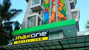 A hotel with a colorful mural on the facade, a green signboard, and a glass entrance. - Maxone Hotels at Malang (Malang)