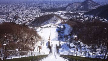 A snow-covered ski slope with a clear view of a cityscape in the background.