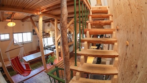 A wooden interior with a spiral staircase, a hanging chair, and a dining area. - SappoLodge - Hostel (Sapporo)