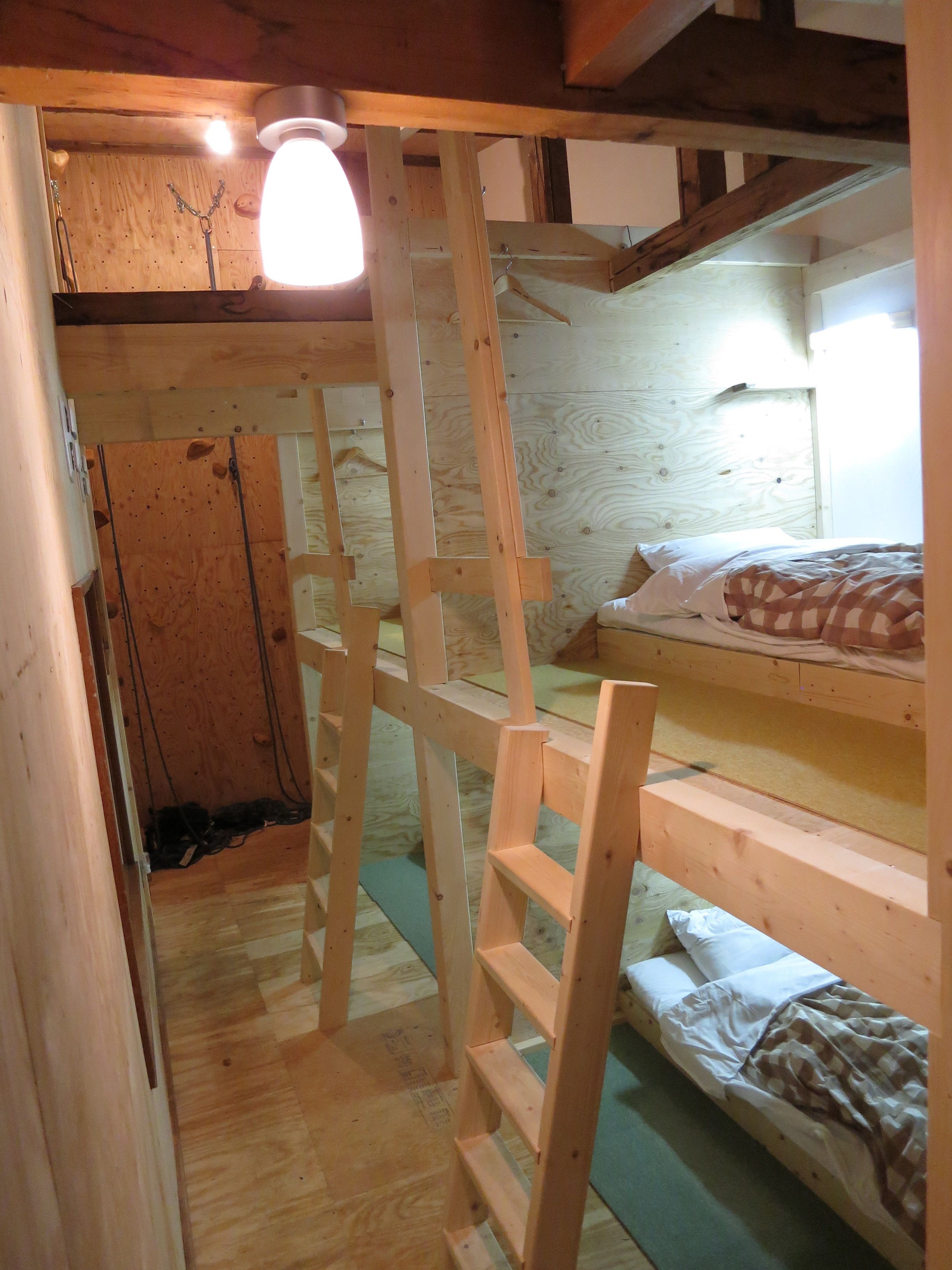 A wooden bunk bed room with a ladder leading to a loft area.