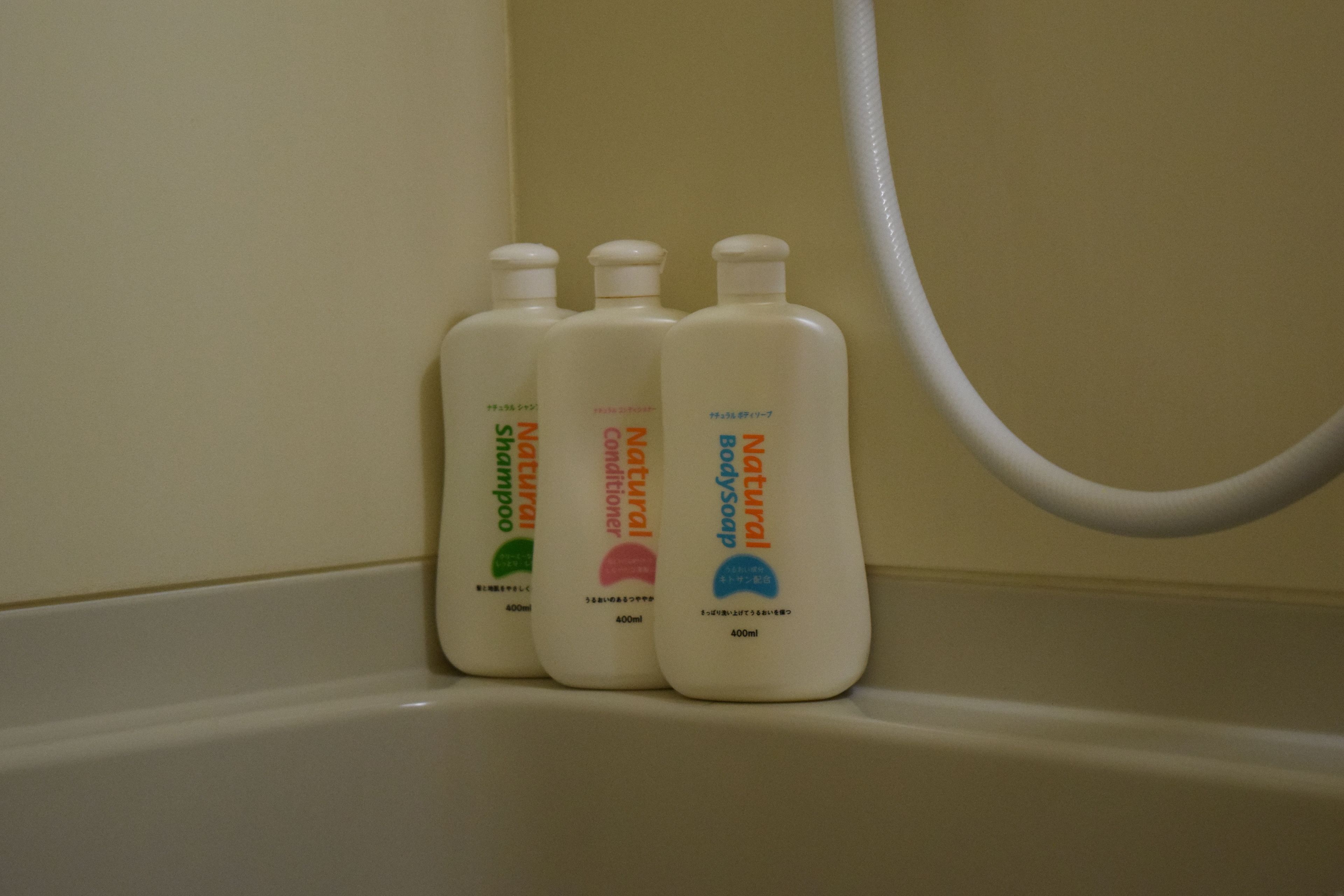 Tres botellas de champú y acondicionador natural en un lavamanos de baño.
