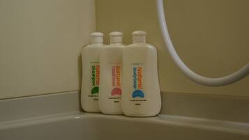 Tres botellas de champú y acondicionador natural en un lavamanos de baño.