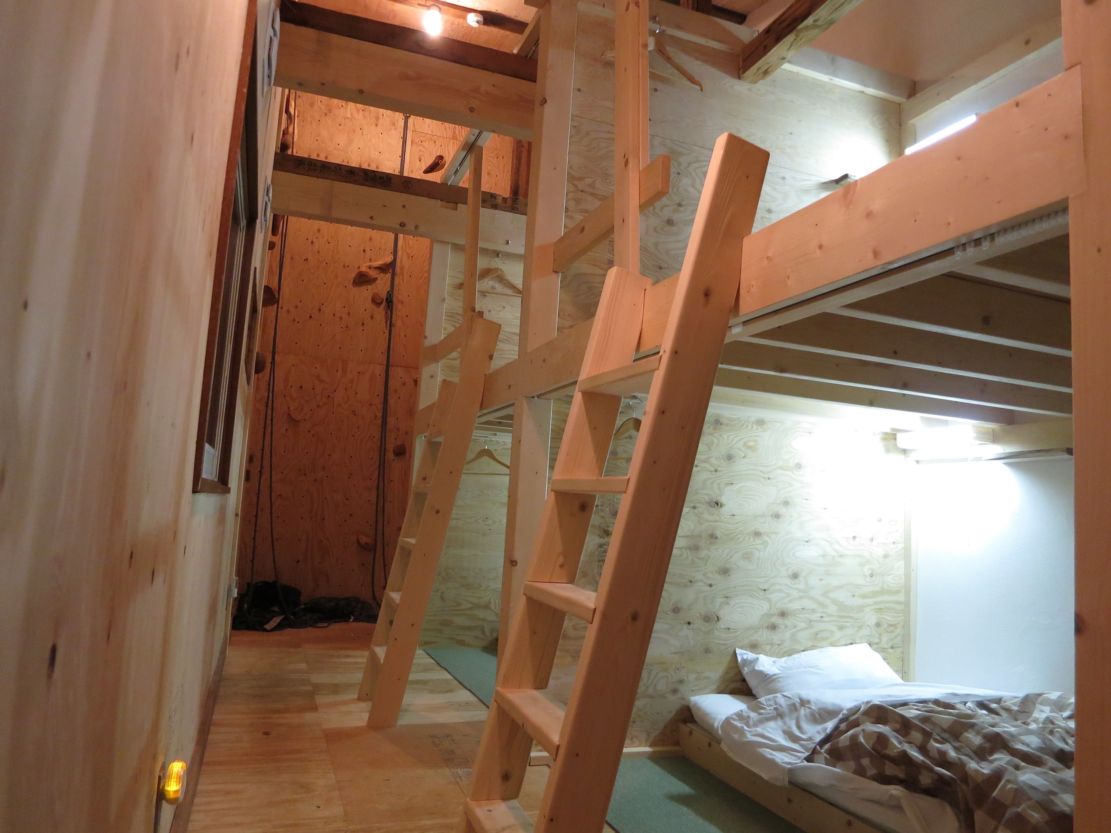 A wooden bunk bed room with a ladder, wooden walls, and a window.