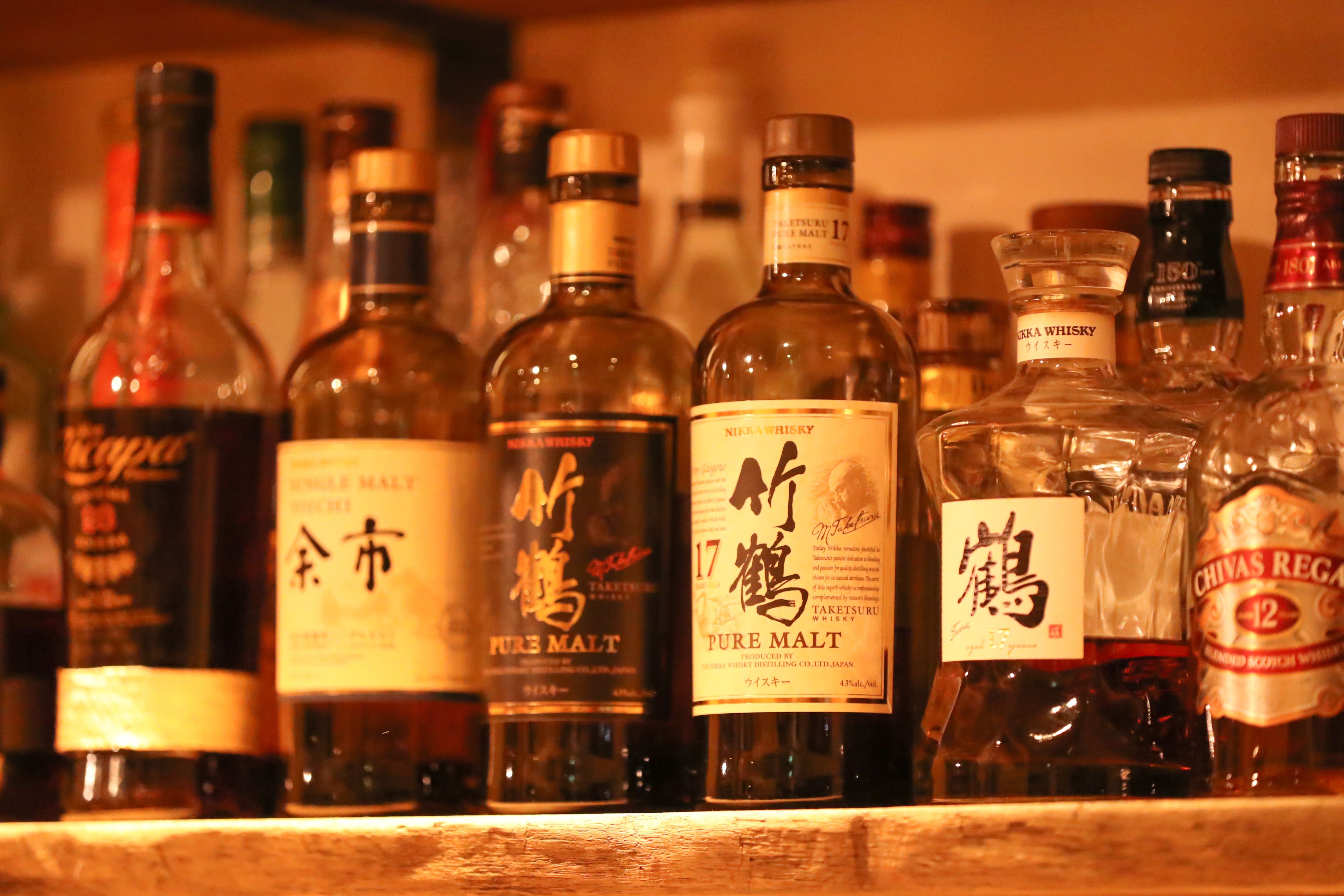 A variety of whisky bottles displayed on a shelf.
