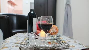 A table with a bottle of red wine, two wine glasses, a candle, and decorative items.