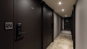 A modern hallway with dark walls, numbered doors, and a digital keycard reader. - About Stay Seoul Station (Seoul)