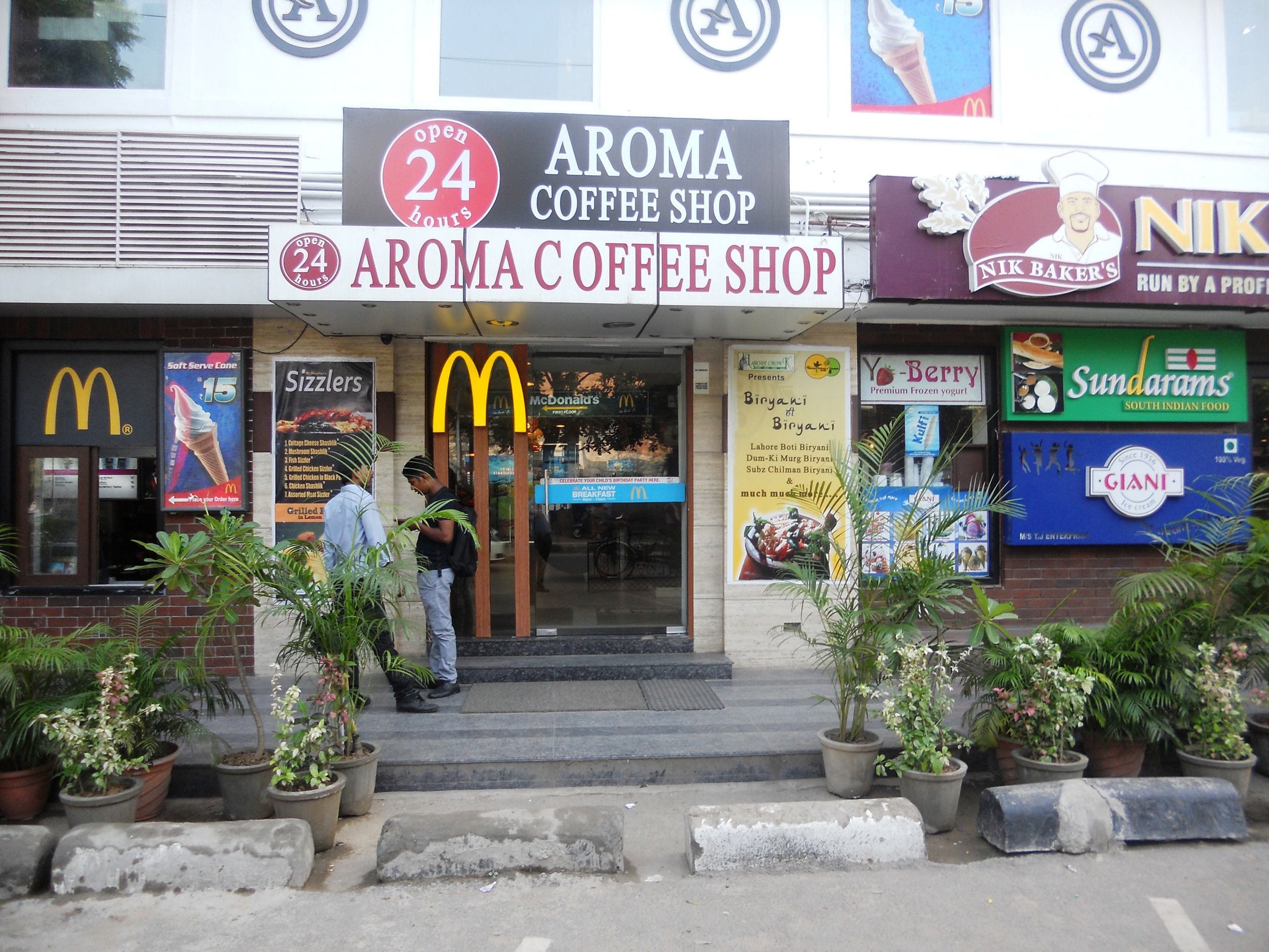 A coffee shop named Aroma Coffee Shop with a 24-hour sign.