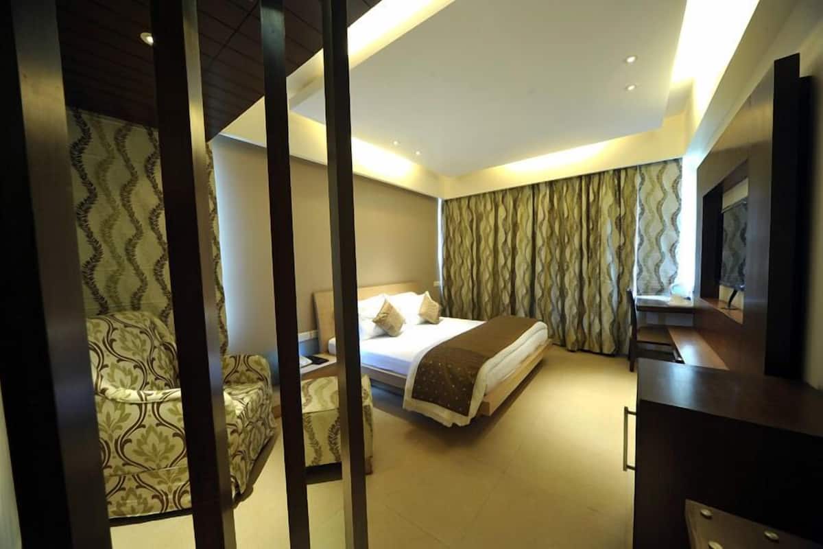 A modern hotel room with a bed, a desk, a chair, and a television.