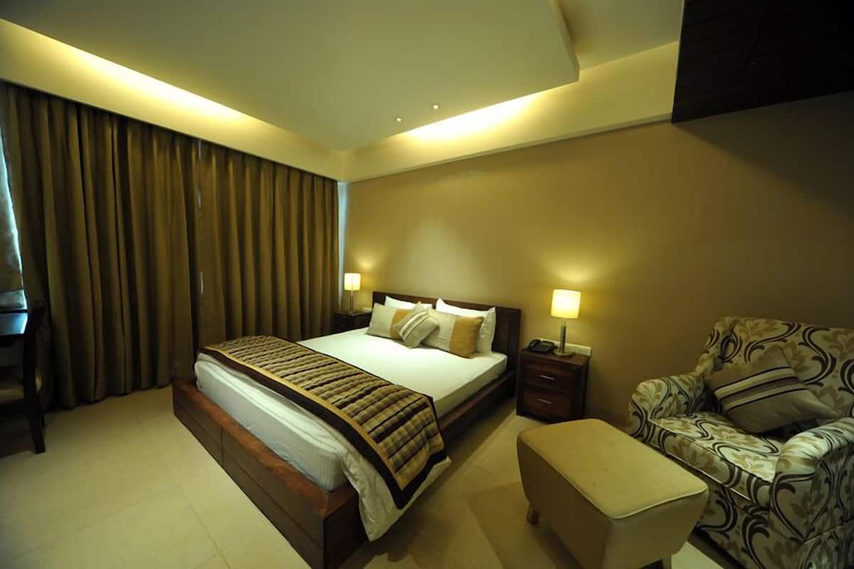 A hotel room with a large bed, a sofa, a chair, and a desk.