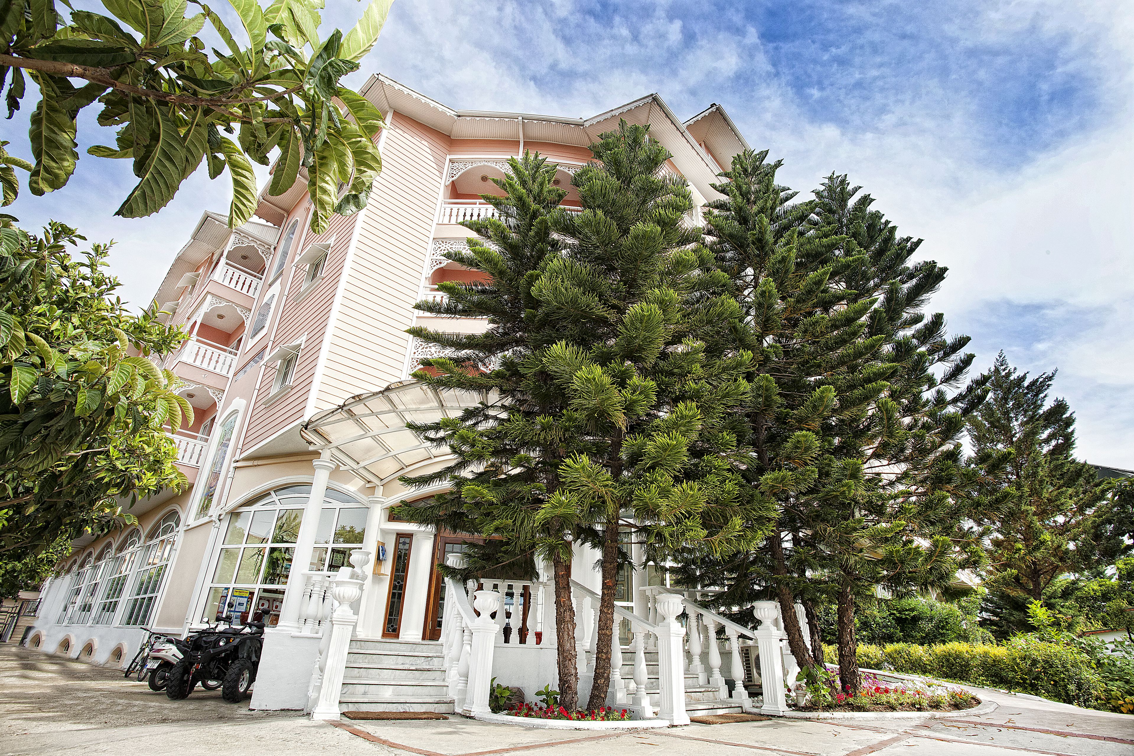 A multi-story hotel with a white facade, balconies, and a covered entrance.