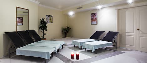 A room with four massage tables, two potted plants, and a door.