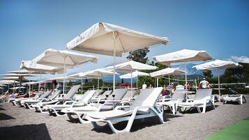 Una playa cerca, sillas reclinables de playa, sombrillas