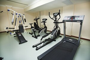 Un gimnasio con varios equipos de ejercicio, incluyendo una cinta de correr, elíptica y máquinas de pesas.