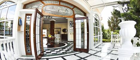 Una entrada imponente con un piso de mármol a cuadros, un letrero que dice "Pasha's Princess" y una puerta de cristal que da al interior.
