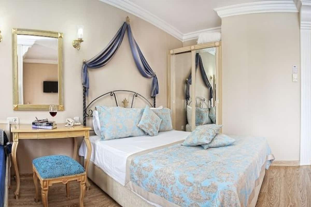 A bedroom with a bed, a desk, a chair, a mirror, and a wardrobe.