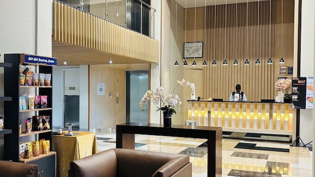 Un hall de hotel con una recepción, un área de descanso y una escalera que sube a un nivel superior.