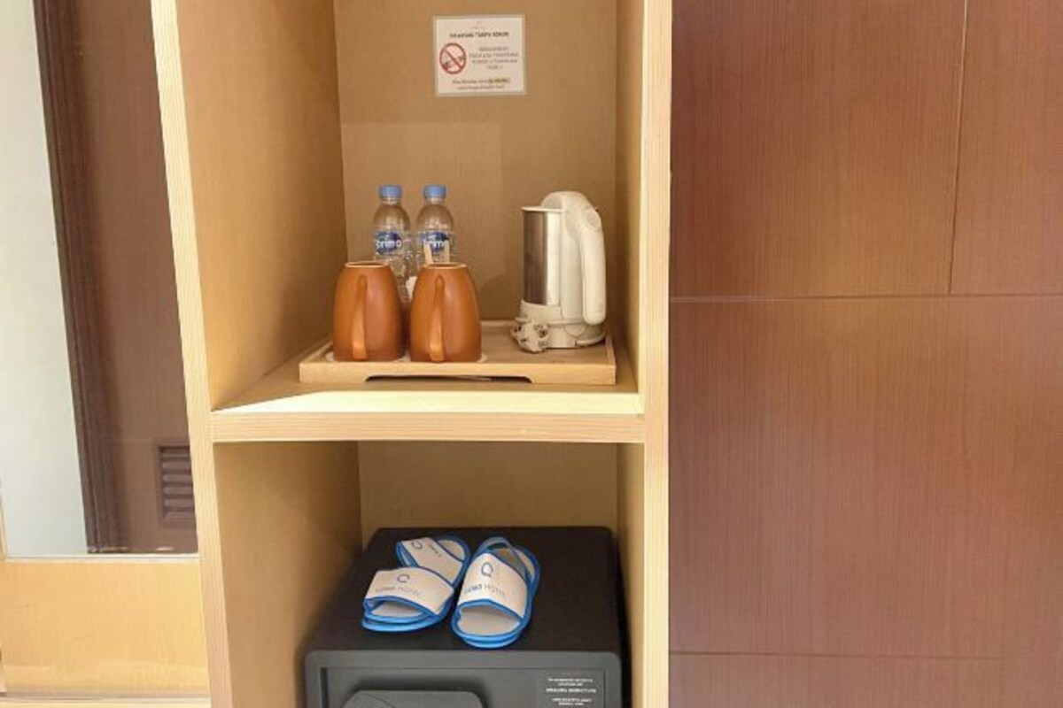 A shelf with two bottles, a kettle, and a pair of slippers.