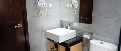 A bathroom with a white sink, a mirror, and two hair dryers mounted on the wall.