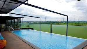 Una piscina al aire libre con vistas a un paisaje urbano y líneas eléctricas al fondo.
