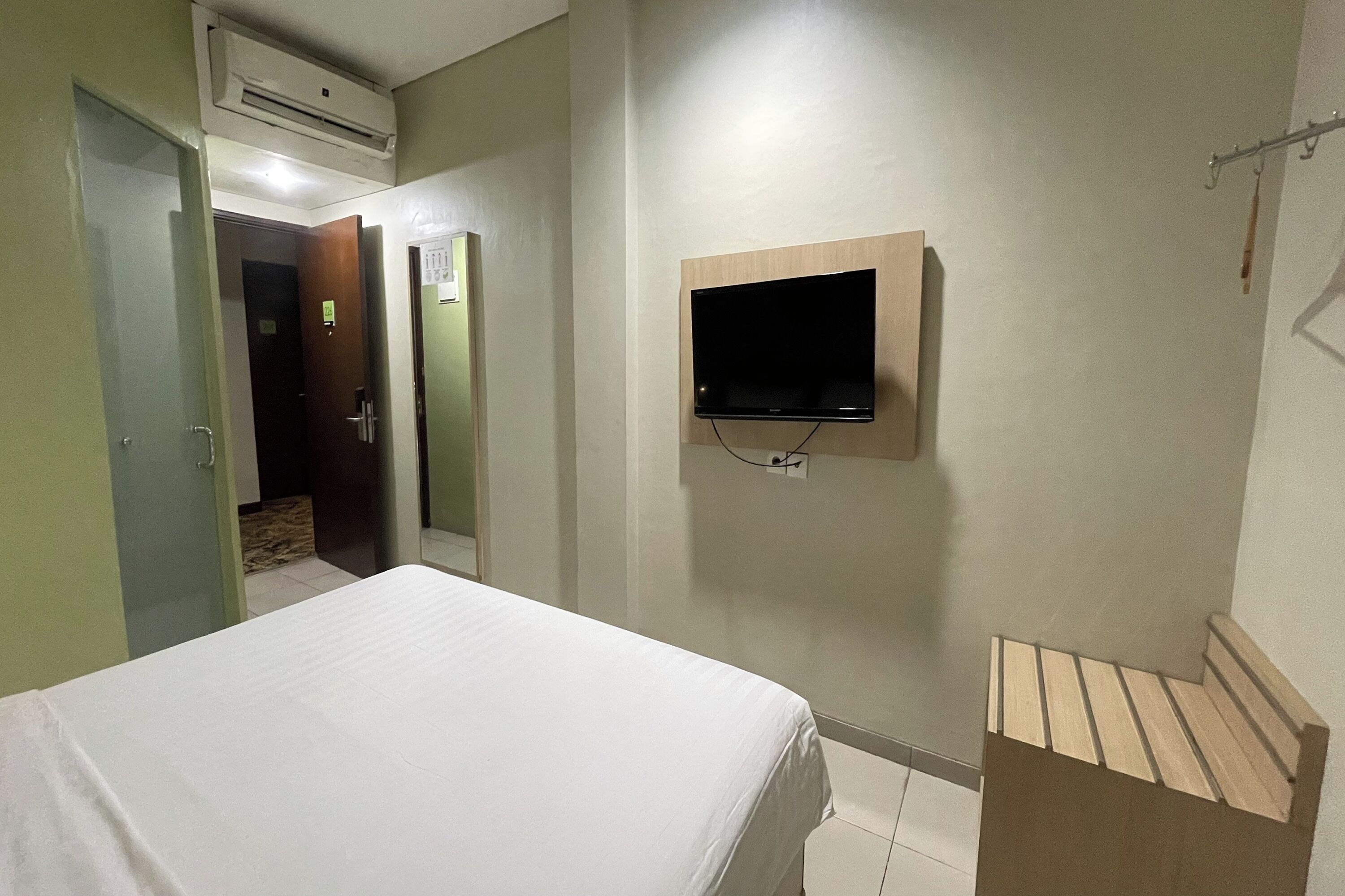 Ein Hotelzimmer mit einem Bett, einem Wandfernseher und einer Klimaanlage.