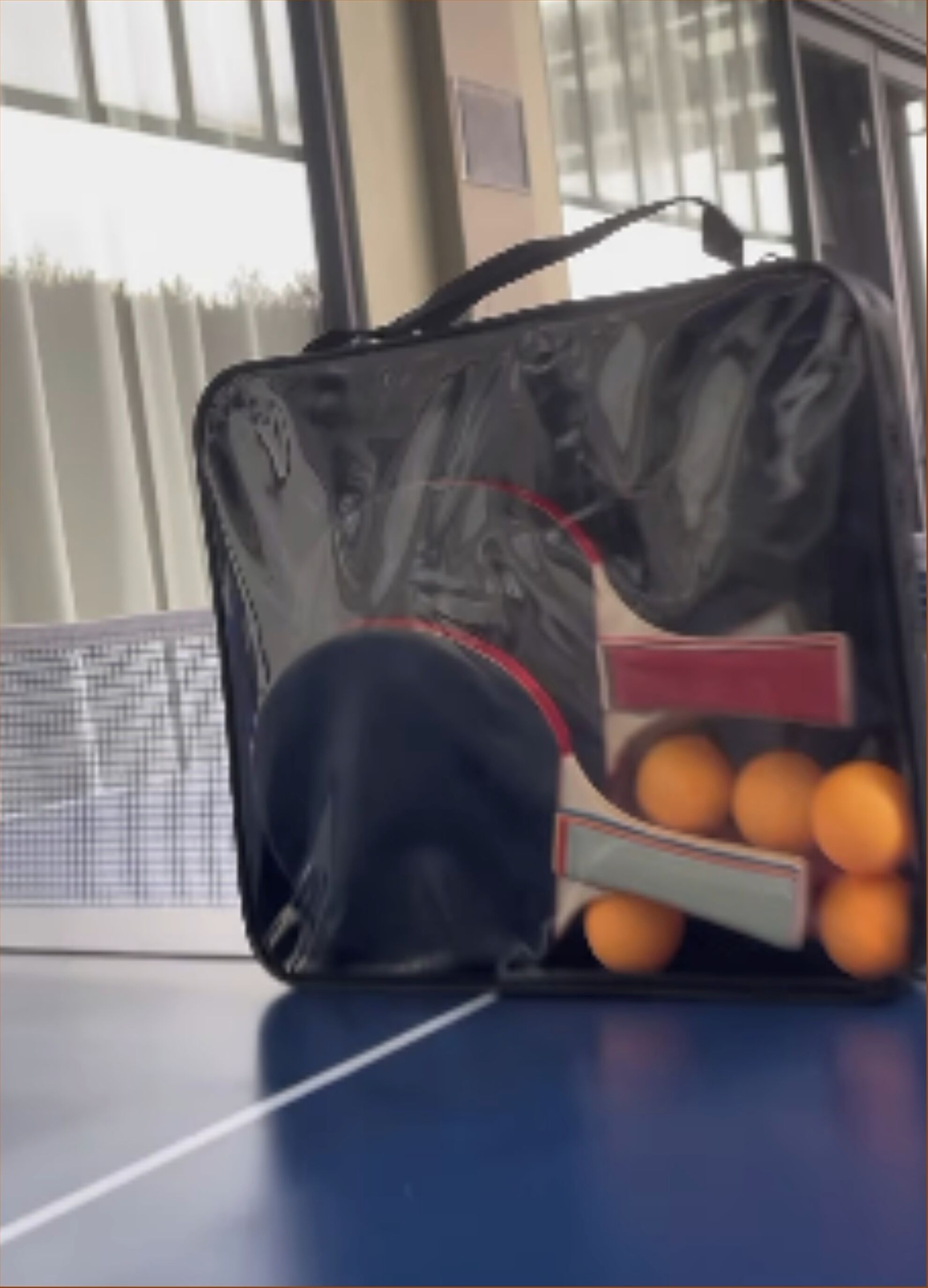 Un sac de tennis contenant une raquette et des balles, posé sur une table.