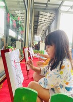 A child painting on a canvas in a room with large windows and a red carpet.