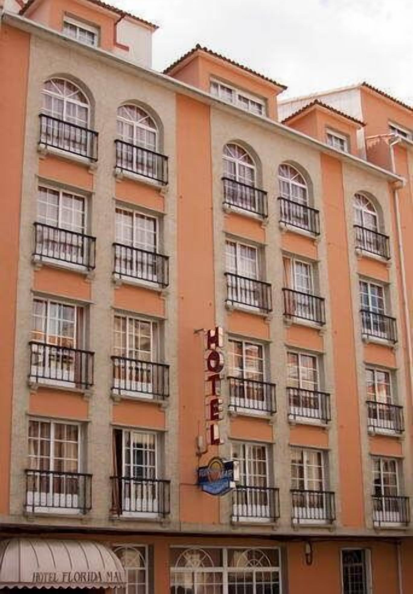 Un hotel de varios pisos con balcones, un cartel que dice “HOTEL” visible, y una vista parcial de un cartel debajo que dice “HOTEL FLORIDA MA.”