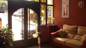 A hotel lobby with a reception desk, a striped sofa, and a large window with a view of the street. - Florida Mar Hotel (Sanxenxo)