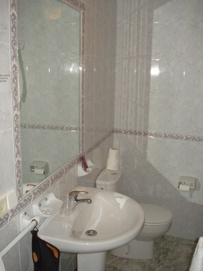 Un baño con lavamanos, inodoro y espejo.