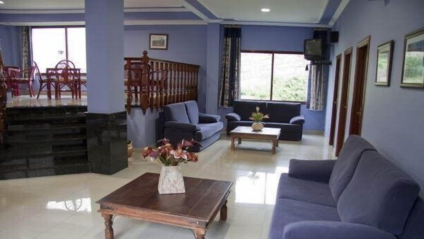 A modern hotel lobby with a blue color scheme, a wooden staircase, a sofa, a coffee table, and a TV. - Florida Mar Hotel (Sanxenxo)