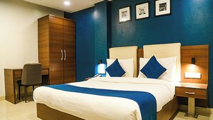 A hotel room with a large bed, a desk, and a wardrobe. - Hotel Concord Galaxy (Mumbai)