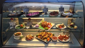A food display case with various dishes and labels. - Hotel Concord Galaxy (Mumbai)