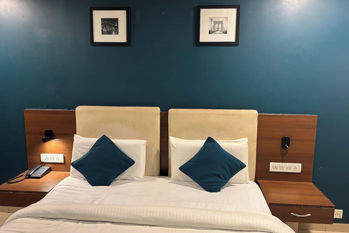 A double bed with two pillows, a bedside table with a phone, and a nightstand with a lamp.