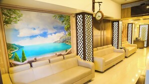 A modern hotel lobby with a large scenic mural, plush seating, and a clock on the wall. - Hotel Concord Galaxy (Mumbai)