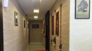 Un pasillo de hotel con una alfombra roja que lleva a una puerta, paredes de madera y cuadros enmarcados.