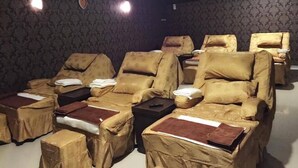 Una sala con varias sillas de masaje cubiertas de tela color beige, dispuestas en filas.