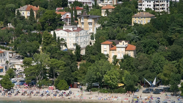 A coastal area with a beach, numerous beach umbrellas, and people. - Hotel Vila Ruzica (Crikvenica)