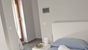 A hotel room with a bed, a nightstand, and a bathroom visible through an open door. - Domus in Viridi (Rome)