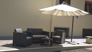 A patio with outdoor furniture, including a sofa and chairs, and a large umbrella providing shade. - Domus in Viridi (Rome)