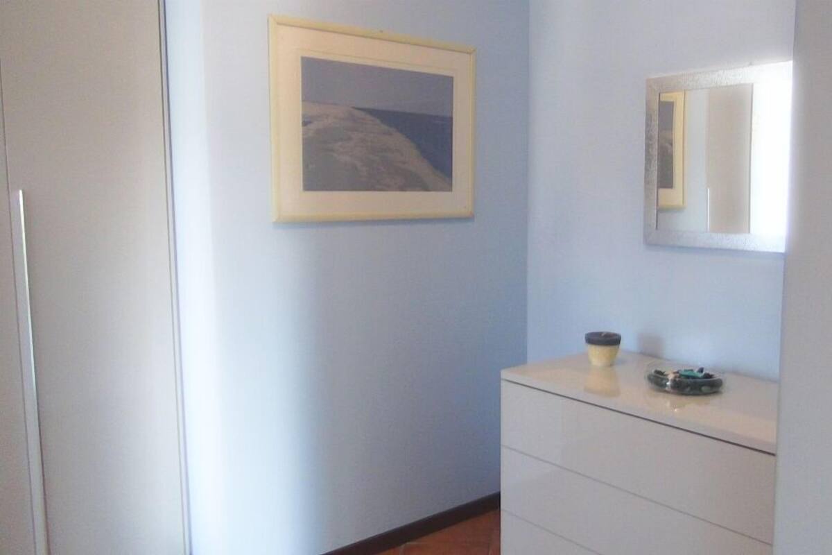 Une pièce avec une commode blanche, un tableau encadré accroché au mur et un miroir au-dessus.