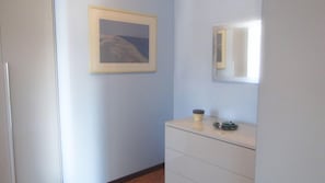 Une pièce avec une commode blanche, un tableau encadré accroché au mur et un miroir au-dessus.