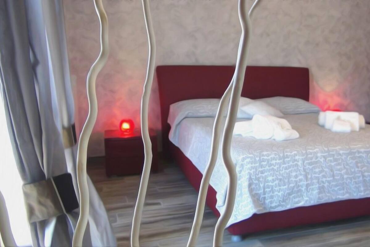 Une chambre à coucher avec un lit, des oreillers, une table de chevet et une commode.