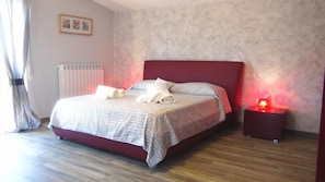 Une chambre à coucher avec un lit, une table de chevet et un radiateur fixé au mur.