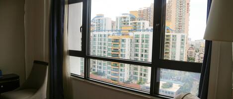 A room with a large window, a chair, a small table, and a lamp.
