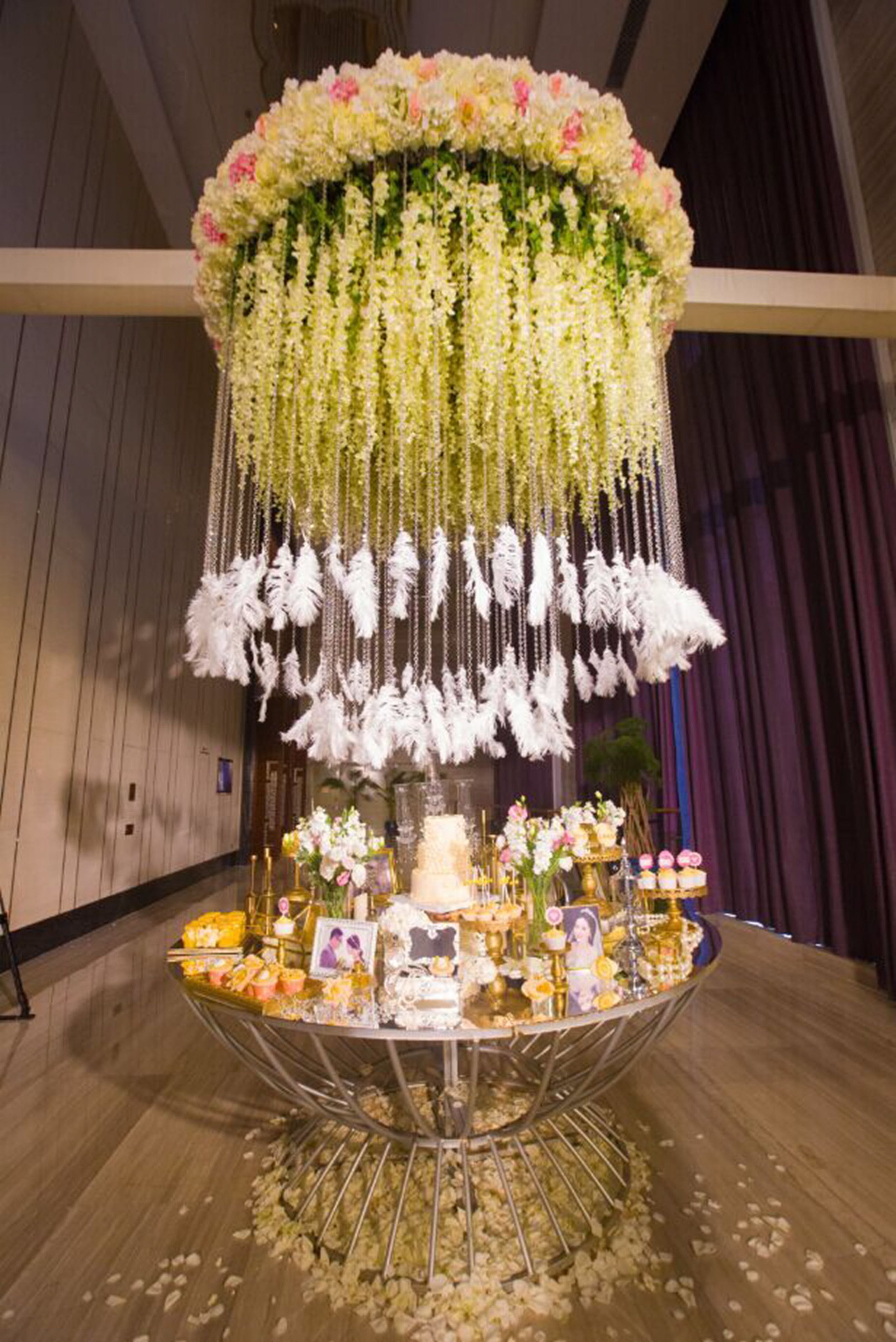 A wedding reception setup with a tiered floral arrangement, a cake, and various decorations on a metal stand.